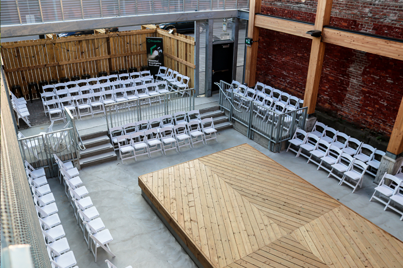 Outdoor theatre with wooden stage and seating on three sides of the stage