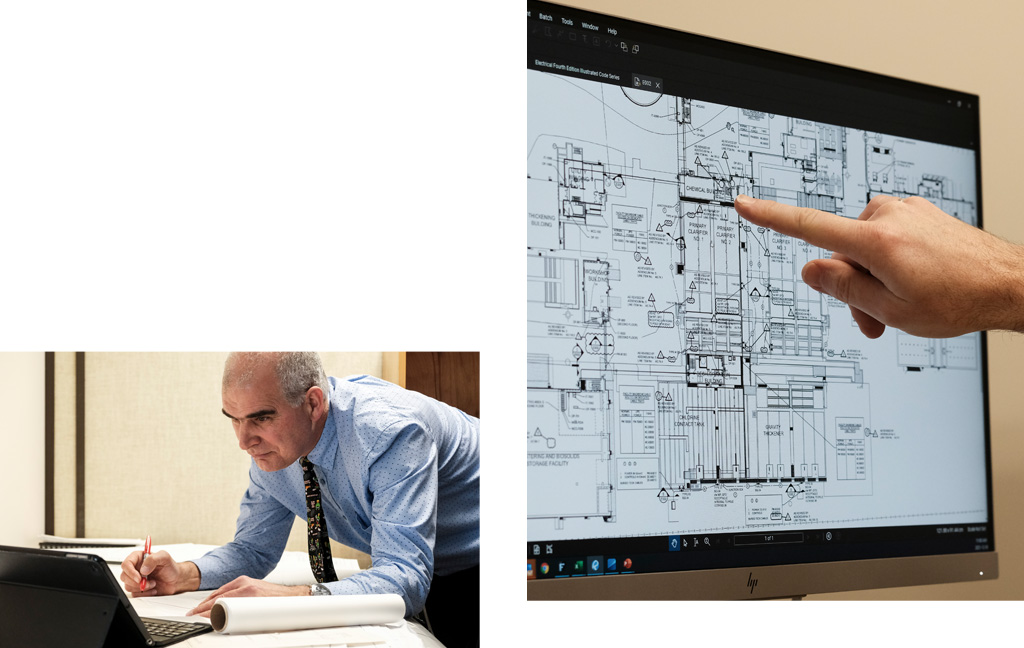 Man working at drafting table with computer, man pointing to drawings on screen