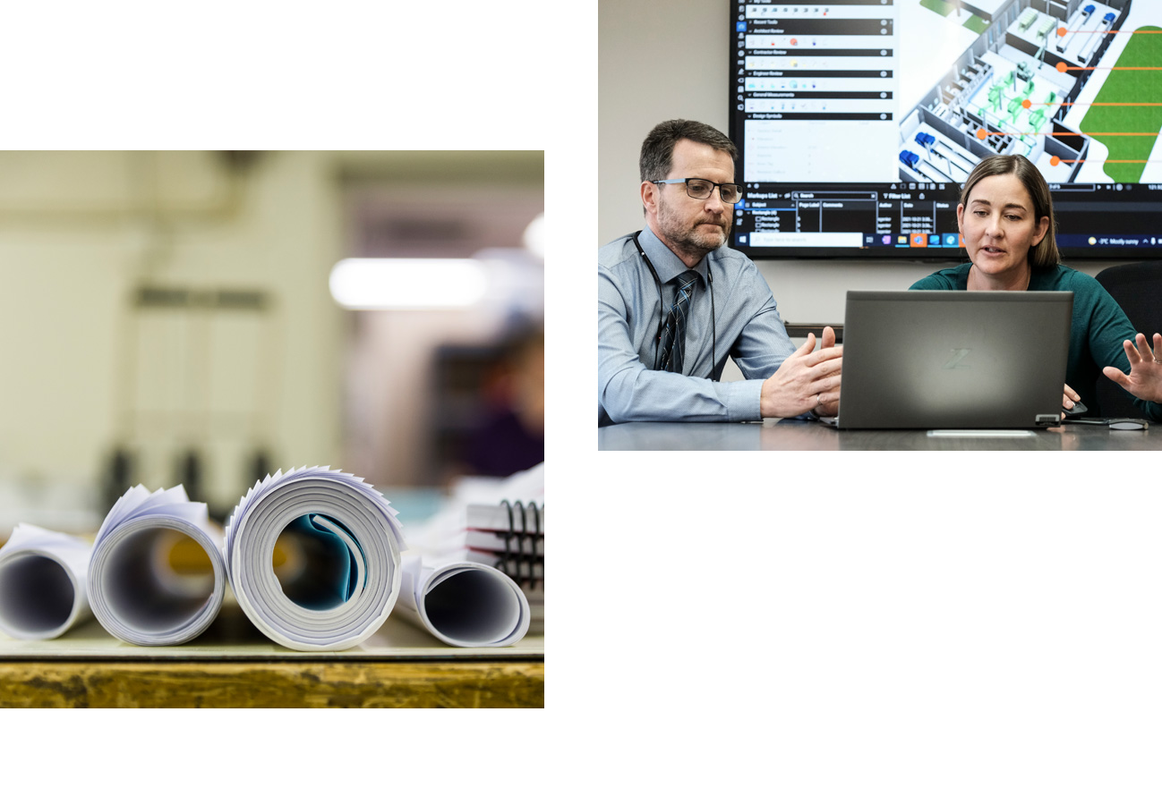 Rolls of technical drawings, man and woman working at computer